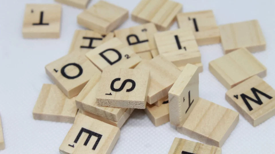 A pile of Scrabble pieces on a white surface.